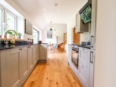A kitchen with gray cabinets wooden floor and dining table at Bluebell Cottage in Mary Tavy
