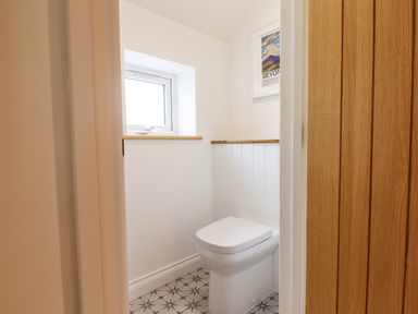 A small bathroom with a toilet window and framed art at Bluebell Cottage in Mary Tavy