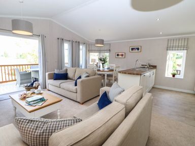 An open plan living area with beige sofas blue cushions a wooden coffee table kitchen island and dining table at Rashierigg in Catterick North Yorkshire
