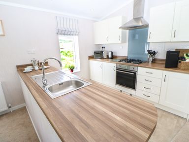 A kitchen with a wooden countertop a sink stove oven microwave and white cabinets at Rashierigg in Catterick North Yorkshire