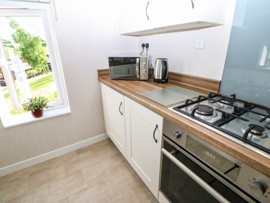 A kitchen with a gas stove oven microwave kettle and a plant on the windowsill at Rashierigg in Catterick North Yorkshire