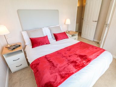 A bedroom with a double bed red blankets bedside tables and lamps at Rashierigg in Catterick North Yorkshire