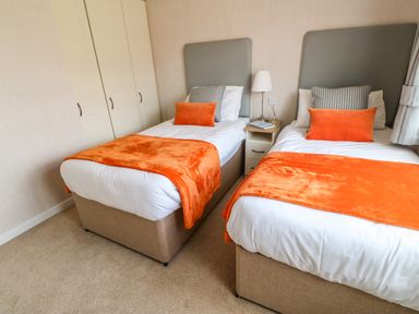 A bedroom with two single beds with orange blankets and pillows at Rashierigg in Catterick North Yorkshire