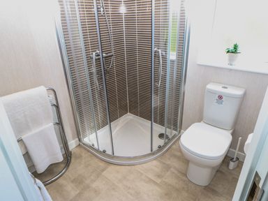 A bathroom with a corner shower unit a toilet and a towel rack at Rashierigg in Catterick North Yorkshire