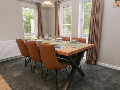 A dining room with a wooden table set with plates glasses and leather chairs at Lily Broadwoodwidger near Ashwater