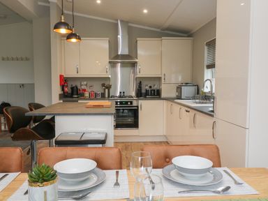 A kitchen with dining table set with bowls and glasses at Lily in Broadwoodwidger near Ashwater