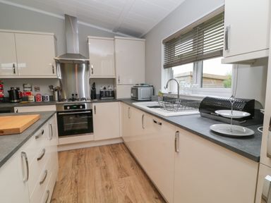A kitchen with white cabinets gray countertops a stainless steel oven gas stove and a window with blinds at Lily Broadwoodwidger near Ashwater