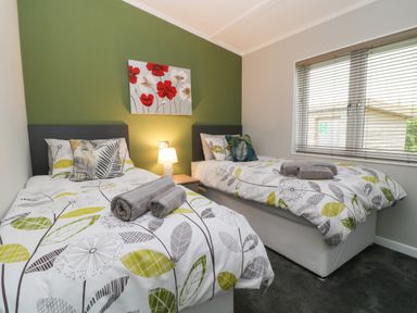 A bedroom with two single beds bedside table lamp and window with blinds at Lily in Broadwoodwidger near Ashwater