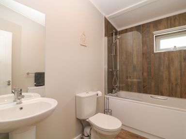 A bathroom with a sink toilet and bathtub with wooden paneling on the wall at Lily in Broadwoodwidger near Ashwater