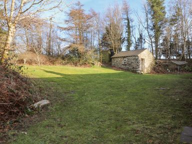 A garden with a stone shed surrounded by trees at Pen y Mynydd in Newport Pembrokeshire