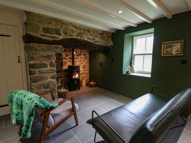 A sitting area with a stone fireplace wood burning stove and two chairs at Pen y Mynydd in Newport Pembrokeshire