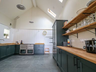A kitchen with dark cabinets wooden countertops open shelves and a stove at Pen y Mynydd in Newport Pembrokeshire