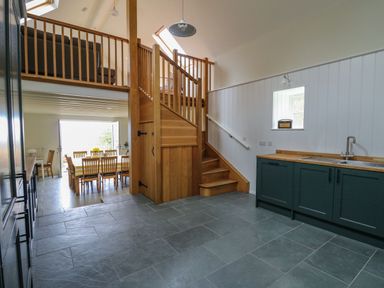 An open kitchen and dining area with wooden stairs and a skylight at Pen y Mynydd in Newport Pembrokeshire