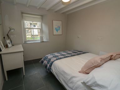 A bedroom with a double bed a desk a window and a framed picture on the wall at Pen y Mynydd in Newport Pembrokeshire