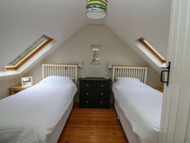 A bedroom with two single beds a black chest of drawers and two skylight windows at Pen y Mynydd in Newport Pembrokeshire