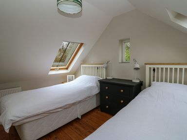 A bedroom with two single beds a black bedside cabinet and windows at Pen y Mynydd in Newport Pembrokeshire