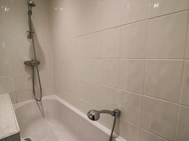A bathroom with a bathtub and showerhead attached to tiled walls at Pen y Mynydd in Newport Pembrokeshire