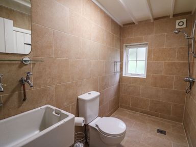 A bathroom with a toilet a sink and a walk in shower with a window at Pen y Mynydd in Newport Pembrokeshire