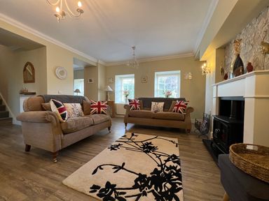 A living room with two sofas and a black and white rug at May Bell Cottage in Dersingham
