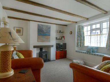 A living room with exposed wooden beams and a wood stove at 12 Mill Green in Lyme Regis