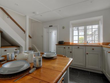 A kitchen with a wooden dining table set with plates cups and a teapot at 12 Mill Green in Lyme Regis