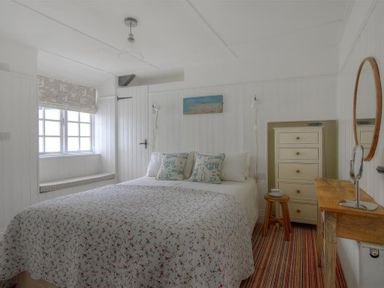 A bedroom with a bed a chest of drawers a stool and a wooden dressing table at 12 Mill Green in Lyme Regis