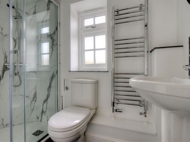 A bathroom with a shower enclosure toilet sink window and a chrome heated towel rail at 12 Mill Green Lyme Regis
