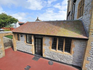 An exterior view of a stone building with a tiled roof windows and a black door at Coram Lodge Lyme Regis