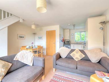 A living room with two gray sofas and a dining table with chairs near a kitchen at 1 Coppers Knapp in Lyme Regis