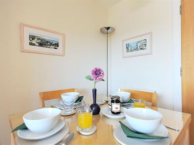 A dining table set with bowls glasses napkins and a flower vase in a dining area at 1 Coppers Knapp Lyme Regis