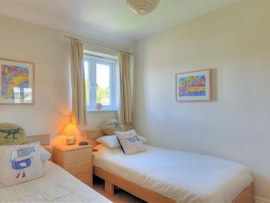 A bedroom with two single beds a bedside table and a window at 1 Coppers Knapp Lyme Regis