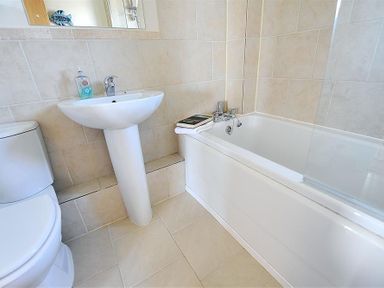 A bathroom with a toilet a pedestal sink and a bathtub with a book on the edge at 1 Coppers Knapp Lyme Regis