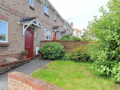A brick house with red doors bushes and a small front garden at 1 Coppers Knapp in Lyme Regis