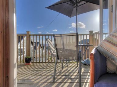 A balcony with chairs a table an umbrella and a potted plant at St Anton in Lyme Regis