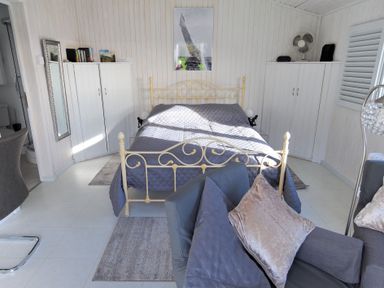 A bedroom with a metal bed frame gray bedding two white wardrobes gray armchairs and a floor lamp at The Cabin in Lyme Regis