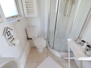 A bathroom with a toilet shower and small table with toiletries at The Cabin in Lyme Regis