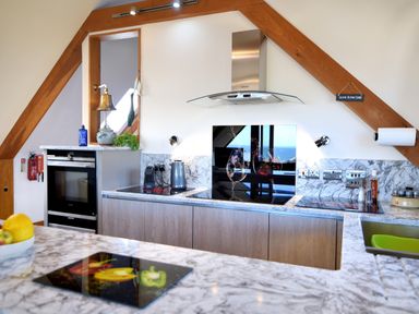 A kitchen with marble countertops an electric stove oven and a sink at Bucket & Spade Lyme Regis