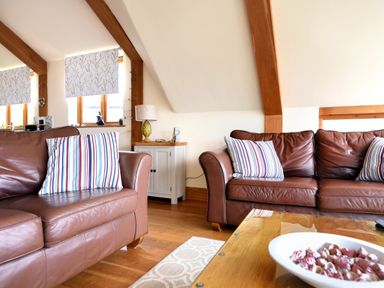 A living room with two brown leather sofas with striped cushions and a wooden coffee table at Bucket & Spade Lyme Regis