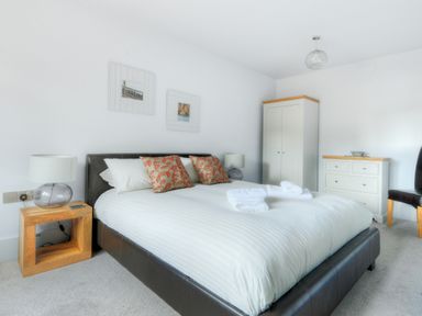 A bedroom with a double bed bedside tables lamps wardrobe and chest of drawers at Bucket & Spade in Lyme Regis