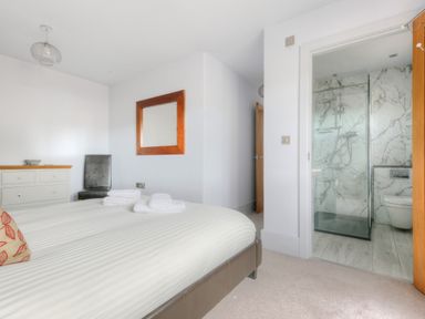 A bedroom with a bed a chair a dresser and an attached bathroom with a shower at Bucket & Spade in Lyme Regis