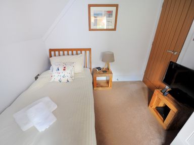 A small bedroom with a single bed wooden furniture and a television at Bucket & Spade Lyme Regis