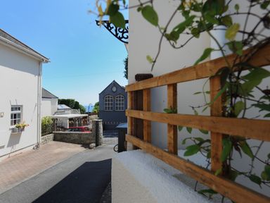 A narrow street with white and grey houses and a wooden trellis with plants at Blacksmiths Cottage in Lyme Regis