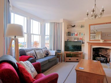 A living room with sofas lamps and a television near a fireplace at 1 Cobb View Lyme Regis