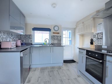 A kitchen with grey cabinets and patterned tile backsplash at 1 Cobb View in Lyme Regis