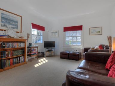 A living room with bookshelves a television and leather sofas at Riverview in Lyme Regis