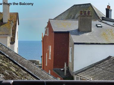 View of rooftops with chimneys and a narrow glimpse of the sea beyond the buildings at Riverview in Lyme Regis