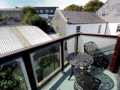 A balcony with a metal table and two chairs overlooking neighboring buildings at Riverview in Lyme Regis