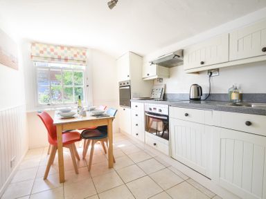 A kitchen with a dining table and chairs near a window at 3 Argyle House in Lyme Regis