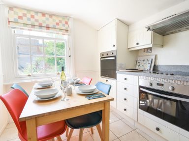 A kitchen with a wooden dining table set for four and a built-in oven at 3 Argyle House in Lyme Regis