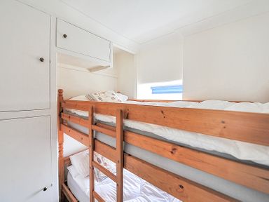 A small bedroom with wooden bunk beds and built in white cupboards at 3 Argyle House in Lyme Regis